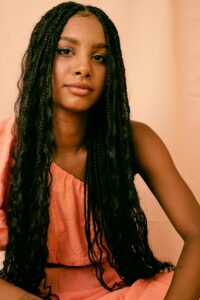 strong black woman posing in front of orange background